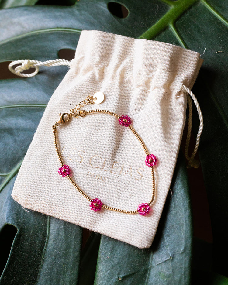 Bracelet avec marguerites roses et détails dorés, vue rapprochée.