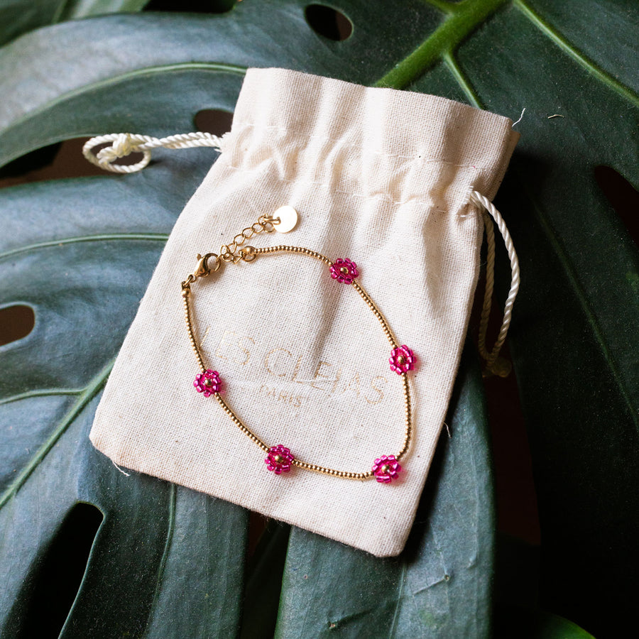 Bracelet avec marguerites roses et détails dorés, vue rapprochée.