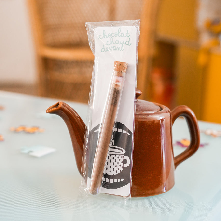 Tube à chocolat chaud avec étiquette colorée et bouchon doré.