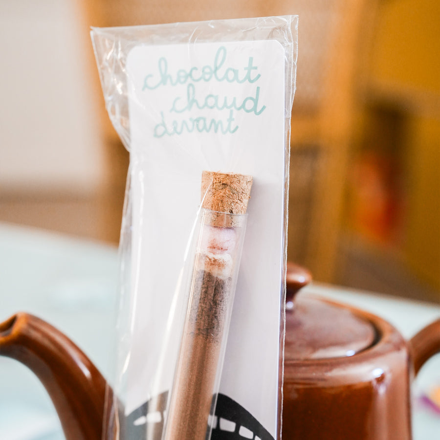 Tube à chocolat chaud avec étiquette colorée et bouchon doré.