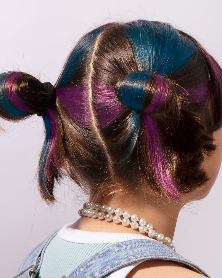 Craies de cheveux colorées en rose, vert et bleu sur fond blanc.