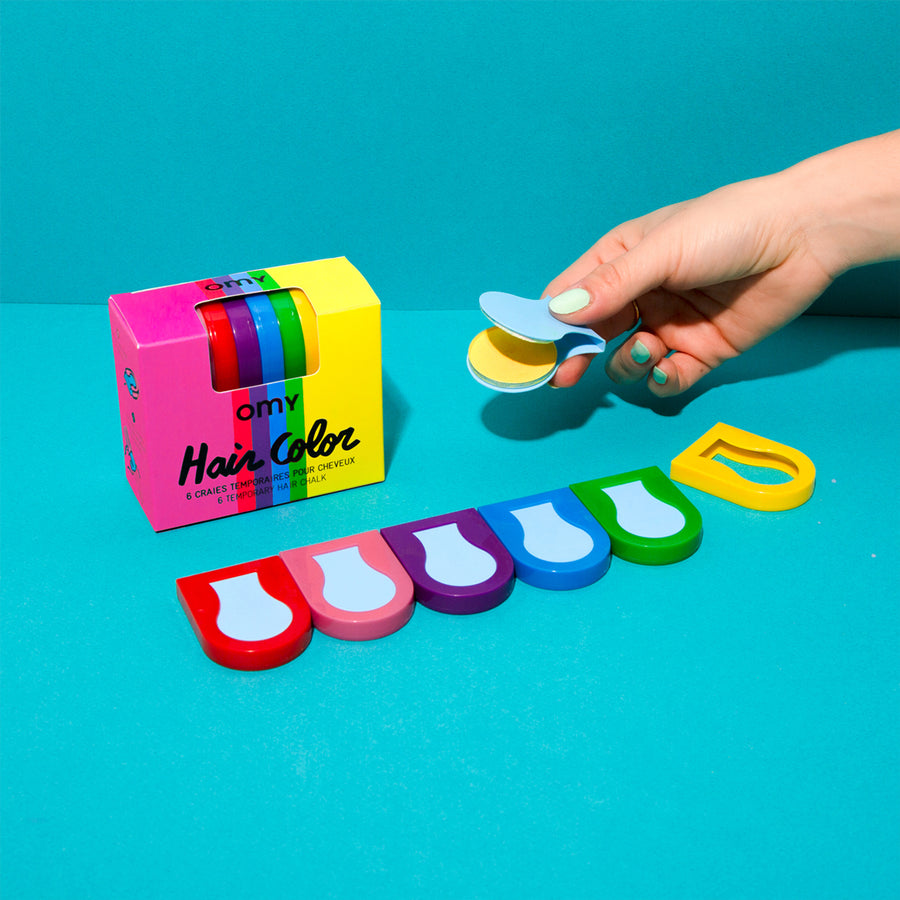 Craies de cheveux colorées en rose, vert et bleu sur fond blanc.