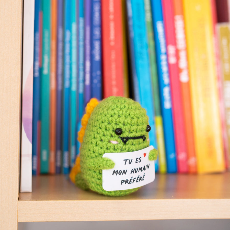 Dino en crochet tenant une pancarte avec un message affectueux.