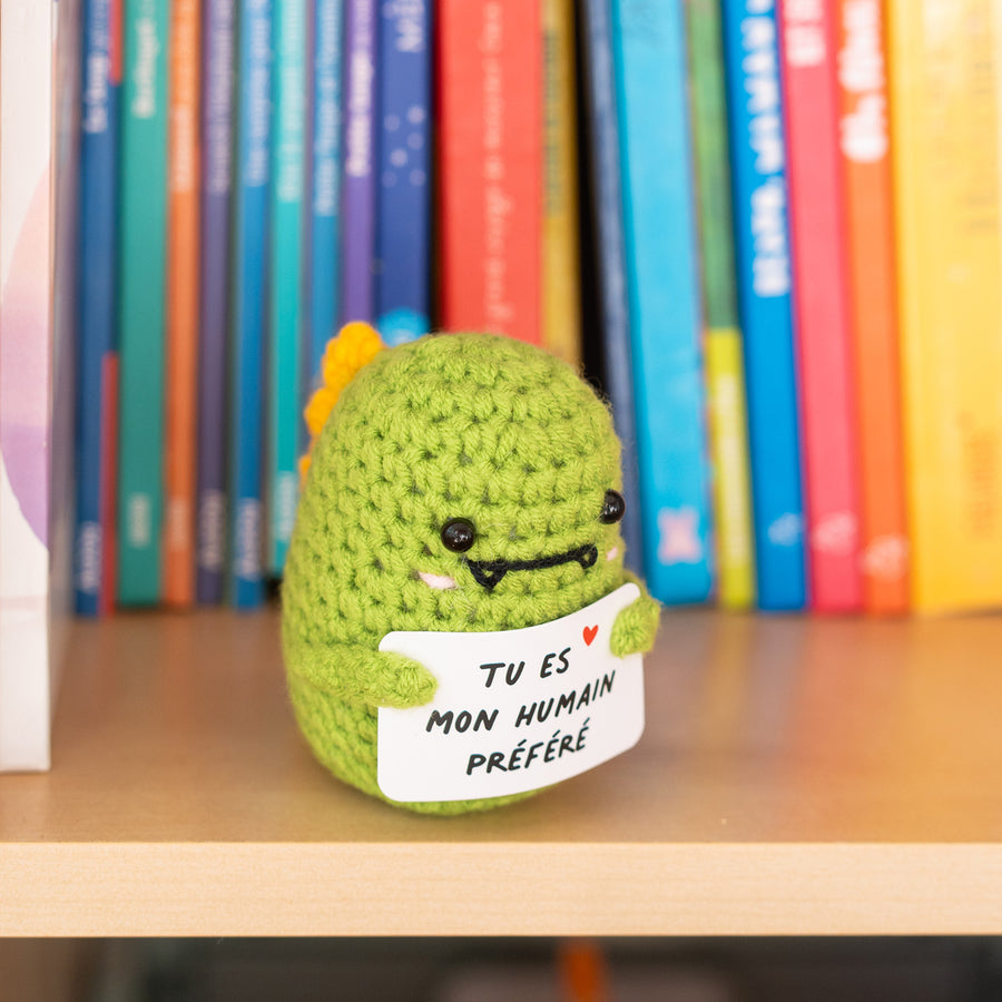 Dino en crochet tenant une pancarte avec un message affectueux.