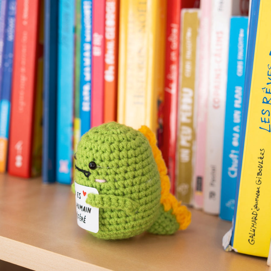 Dino en crochet tenant une pancarte avec un message affectueux.