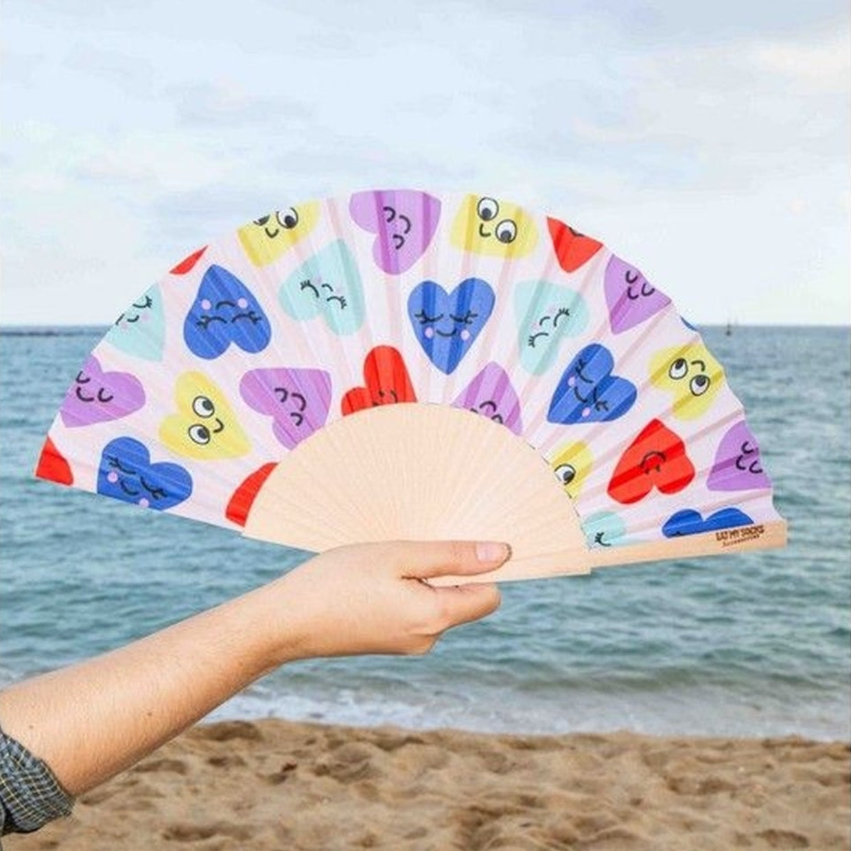 Éventail compact décoré de cœurs, ouvert sur fond clair