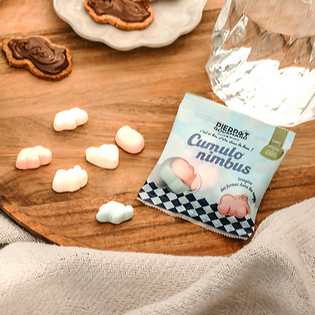 Sachet de guimauves nuage pastel posé parmi des bonbons moelleux sur un plateau