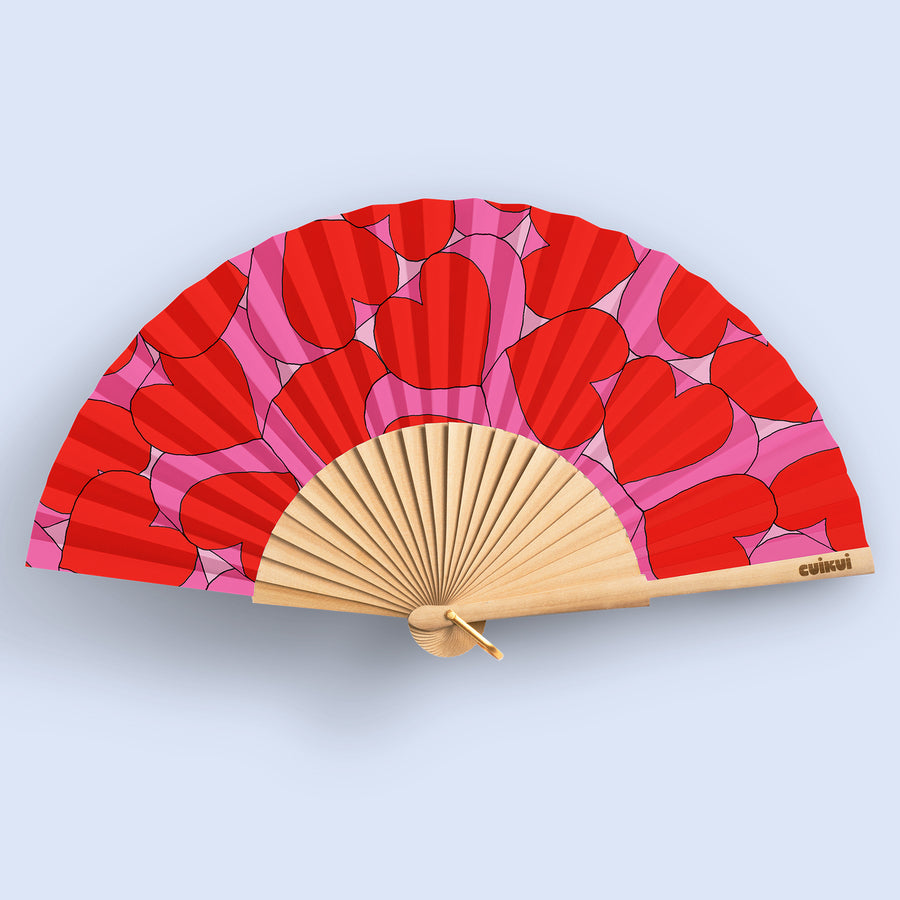 Éventail déployé avec motifs de cœurs roses et rouges