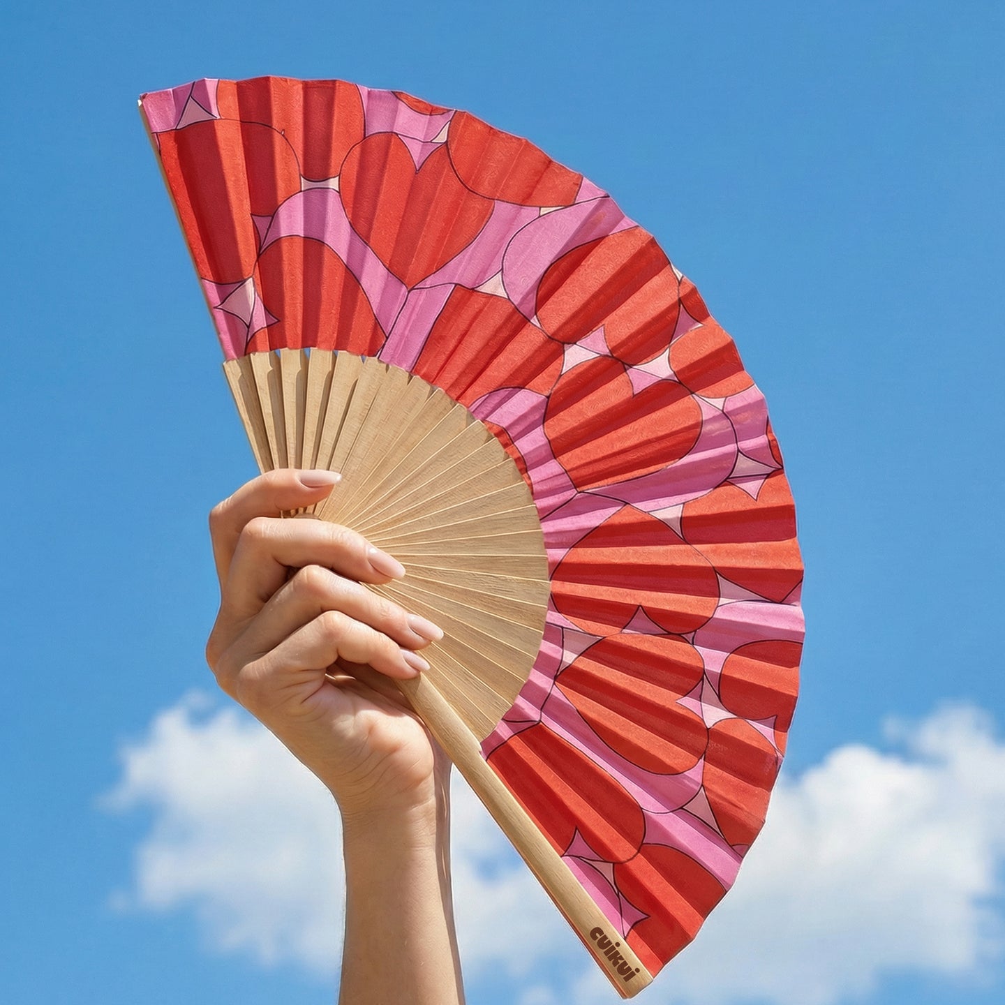 Éventail déployé avec motifs de cœurs roses et rouges