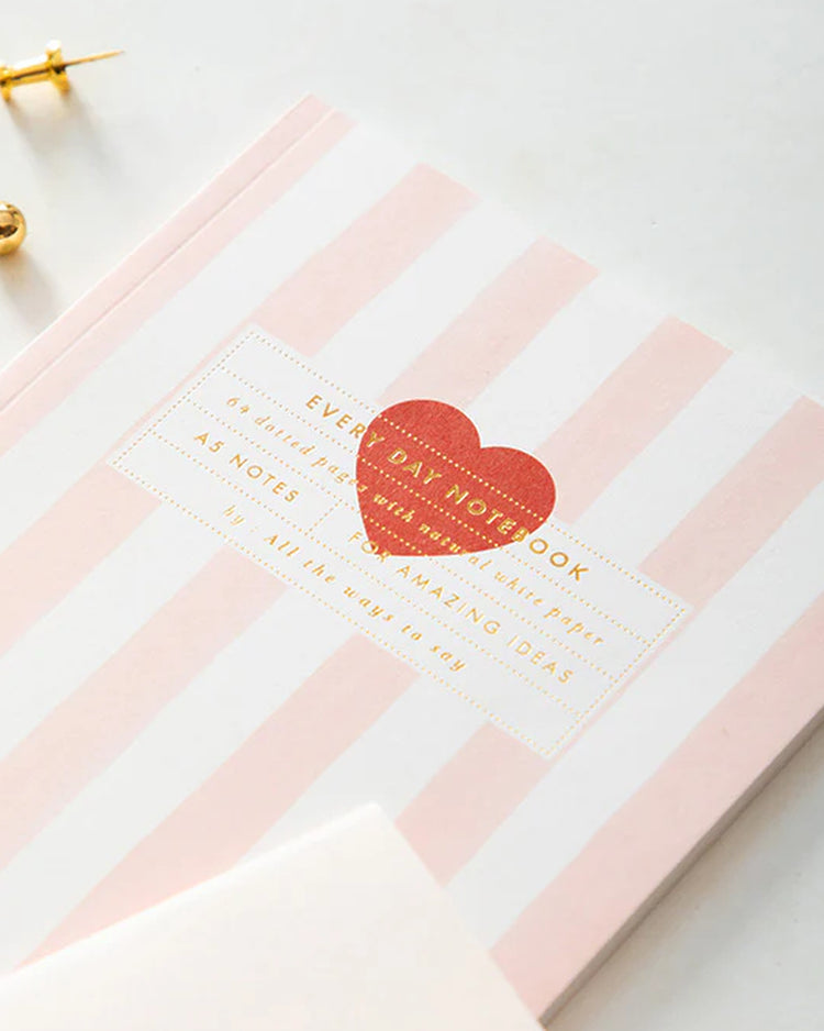 Carnet rayé rose avec motif cœur rouge sur la couverture