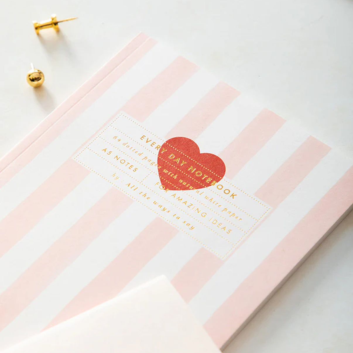 Carnet rayé rose avec motif cœur rouge sur la couverture