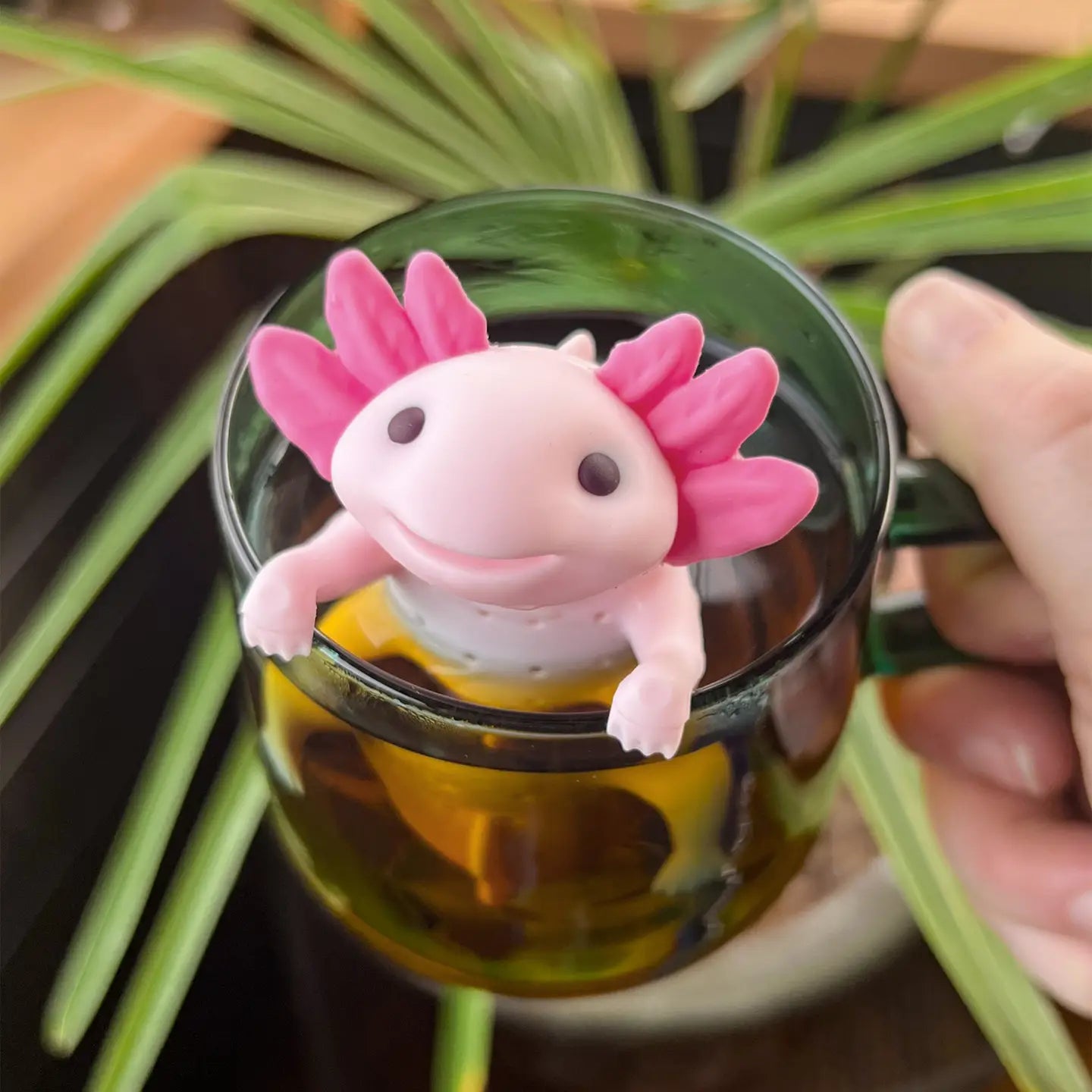 Infuseur à thé axolotl suspendu au bord d'une tasse