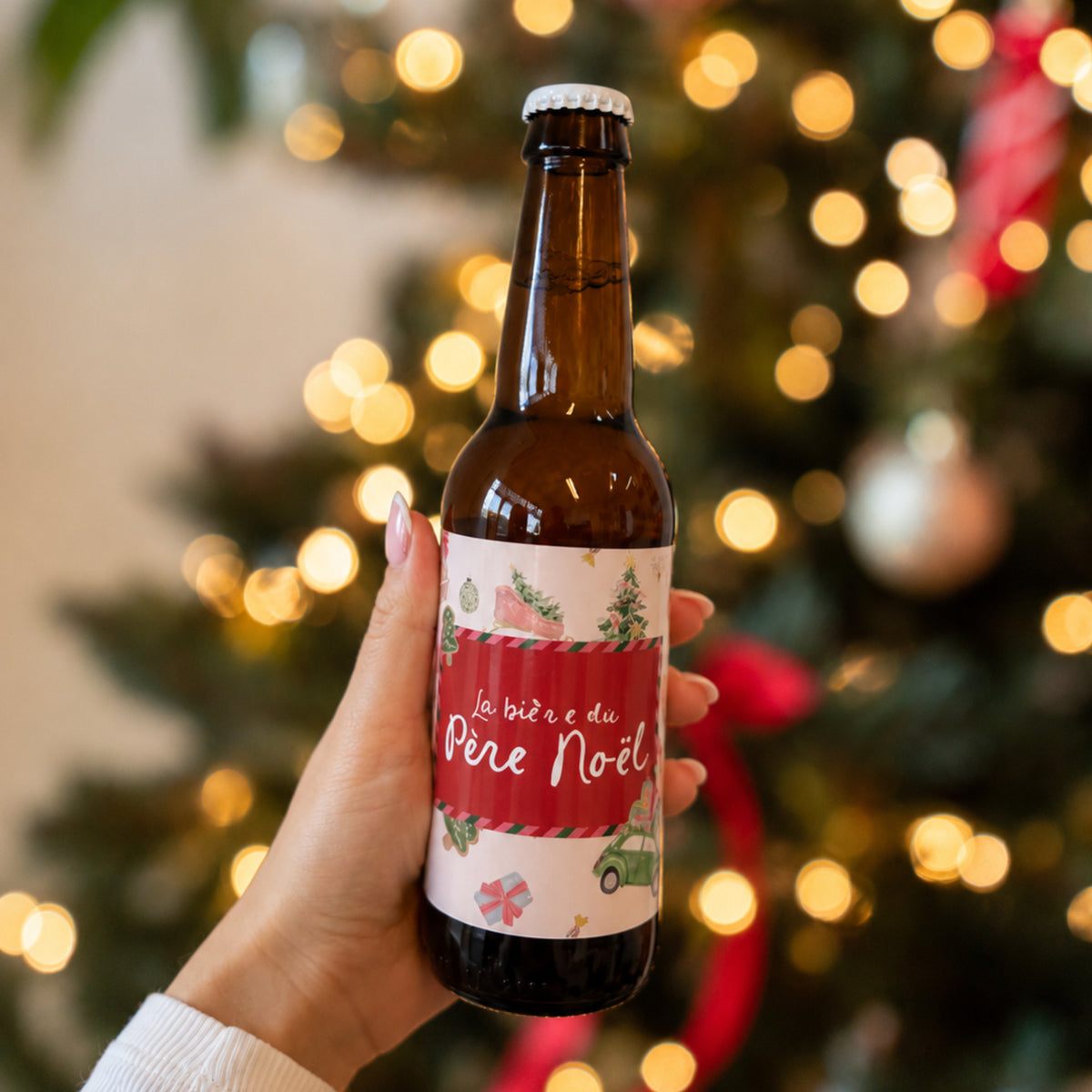 Bouteille de bière tenue en main, étiquette rouge illustrée sur fond de lumières
