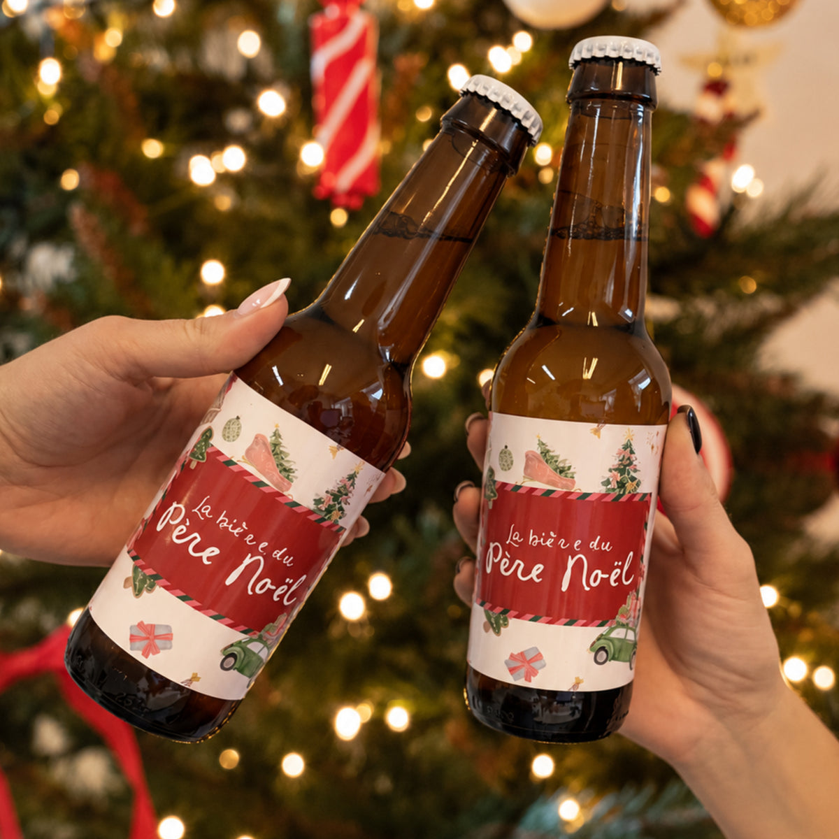 Deux bières du Père Noël aux étiquettes festives, levées devant un sapin illumin