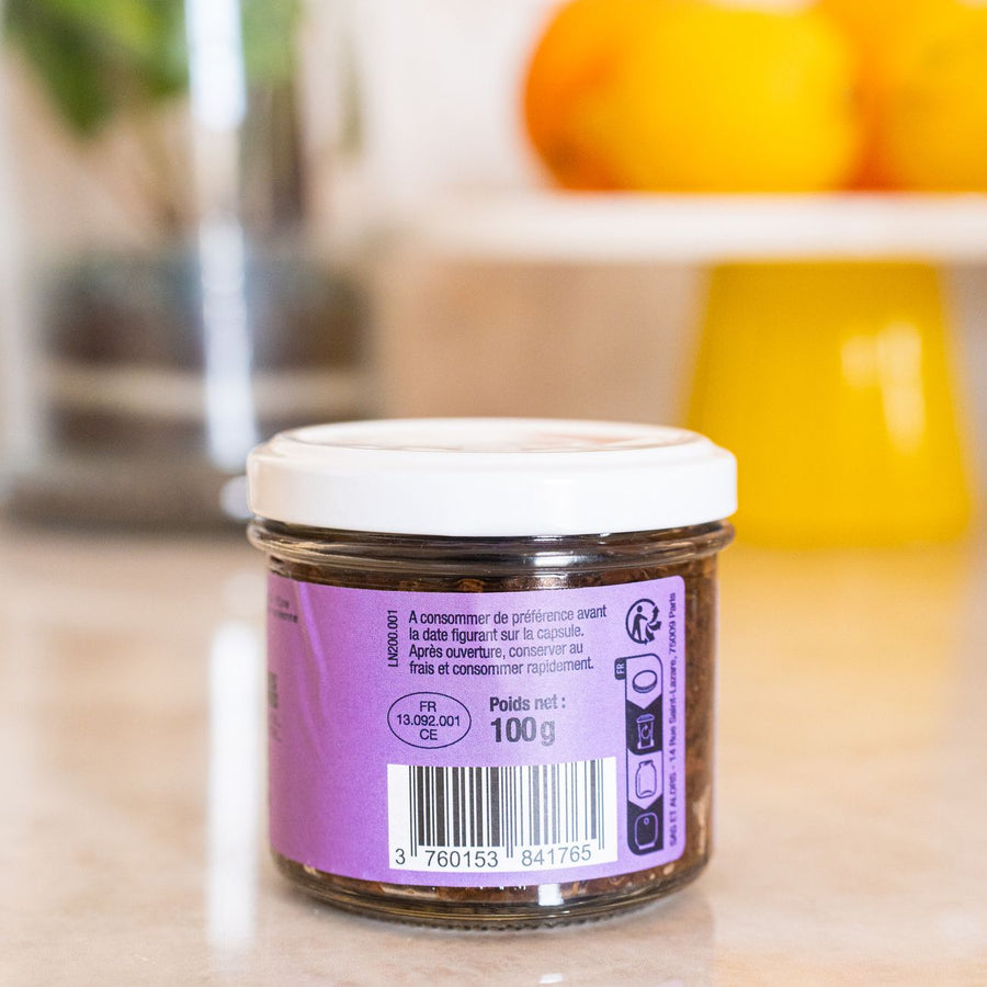 Pot de tapenade noire avec texture crémeuse et olives visibles.