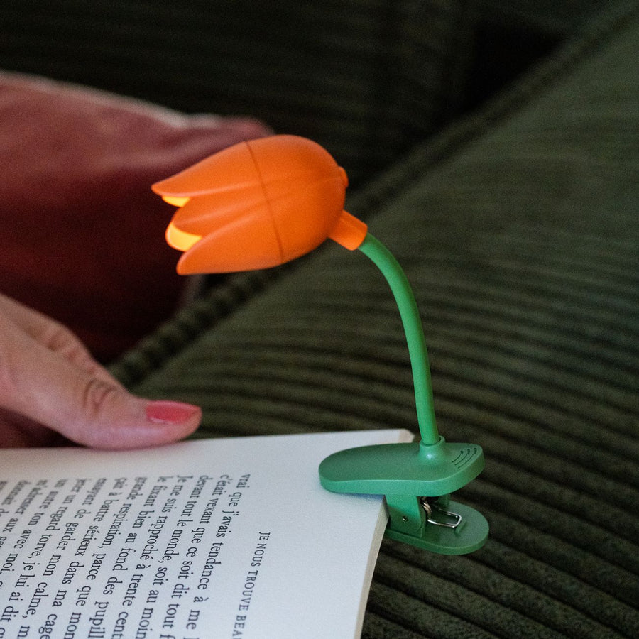 Liseuse tulipe compacte, éclairage doux sur pages de livre.