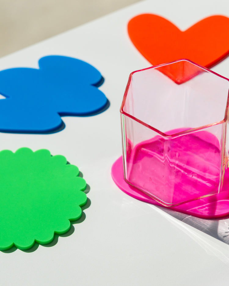 Quatre sous-verres colorés aux formes ludiques sur une table