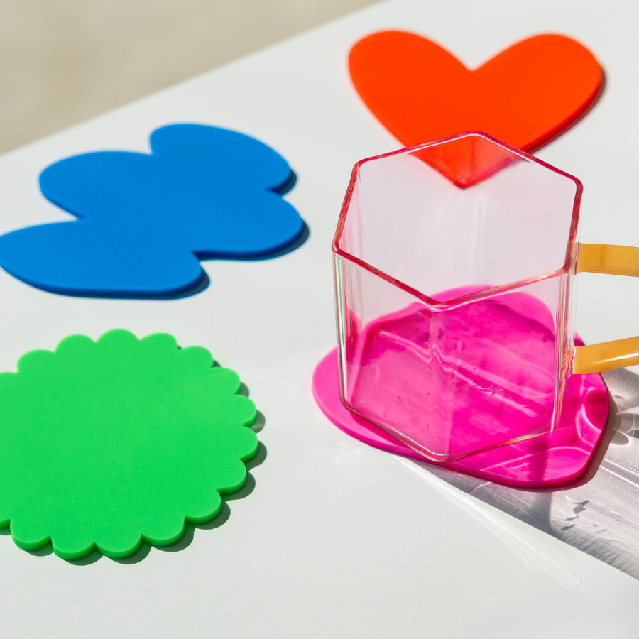Quatre sous-verres colorés aux formes ludiques sur une table