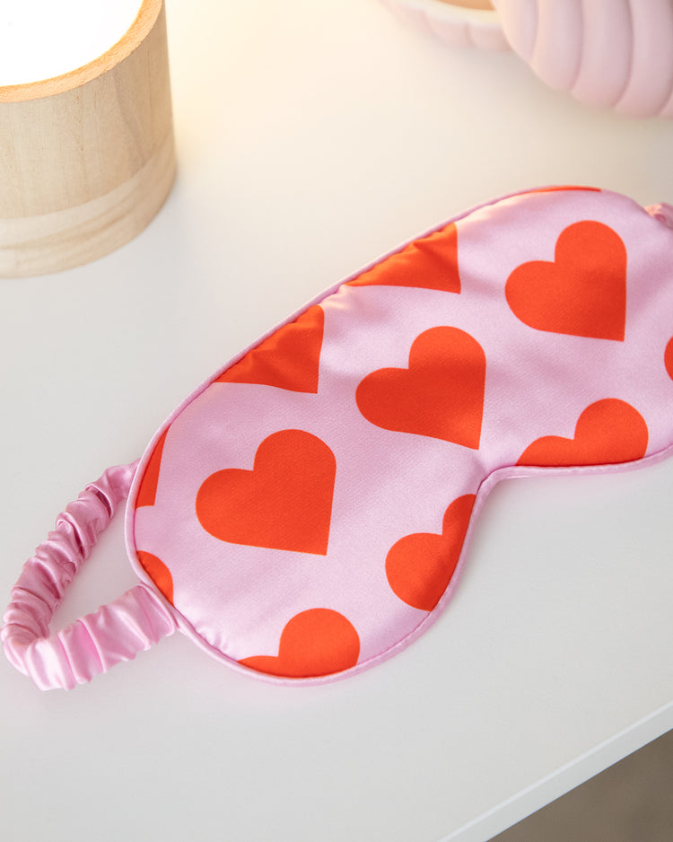 Masque de sommeil rose avec motifs de cœurs sur fond clair