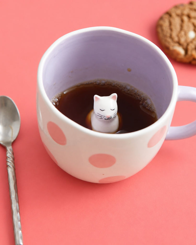 Mug rose et blanc avec un chat caché à l'intérieur