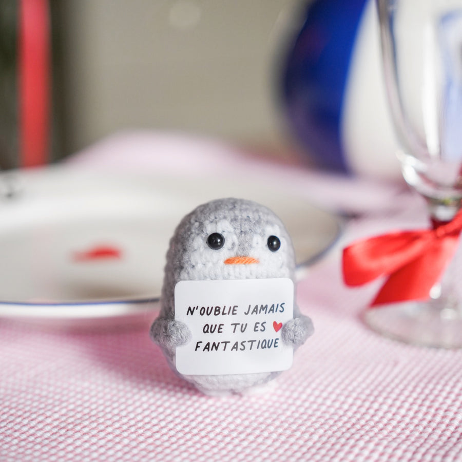 Peluche pingouin en crochet avec message inspirant sur le ventre.