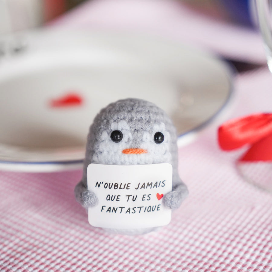 Peluche pingouin en crochet avec message inspirant sur son ventre.