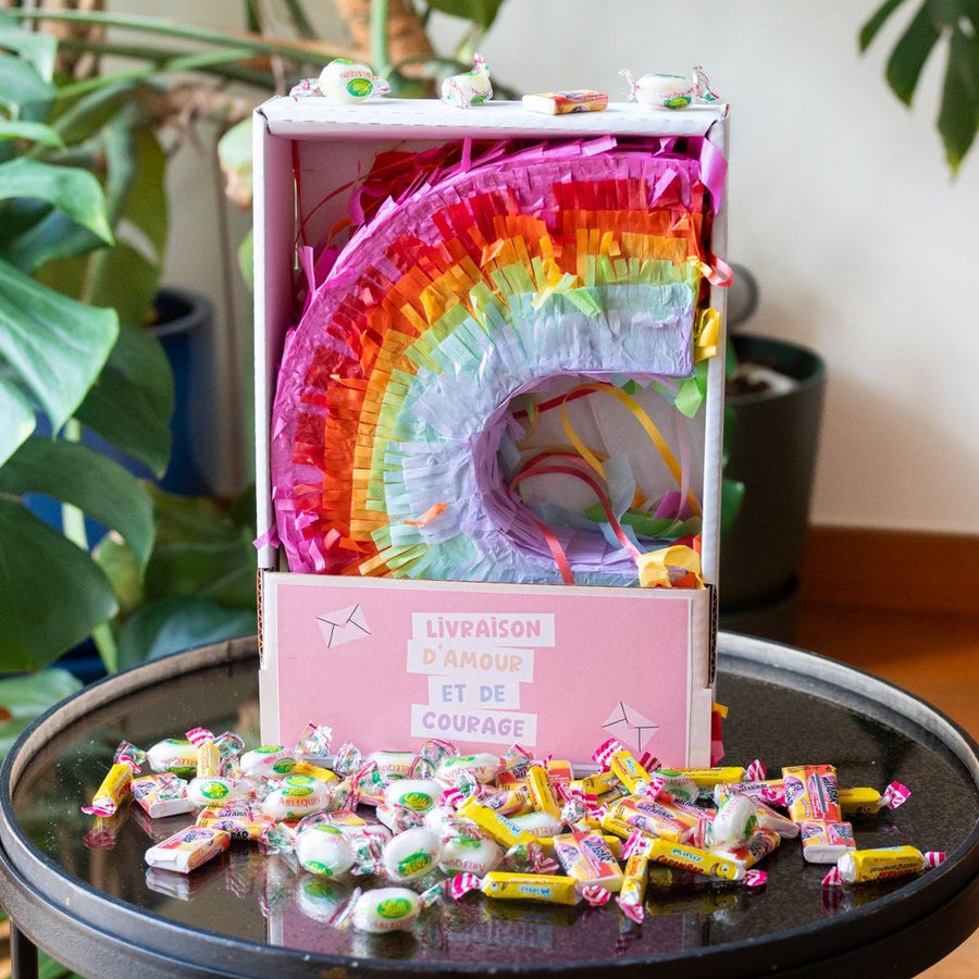 Piñata arc-en-ciel vue de face avec bonbons colorés visibles.