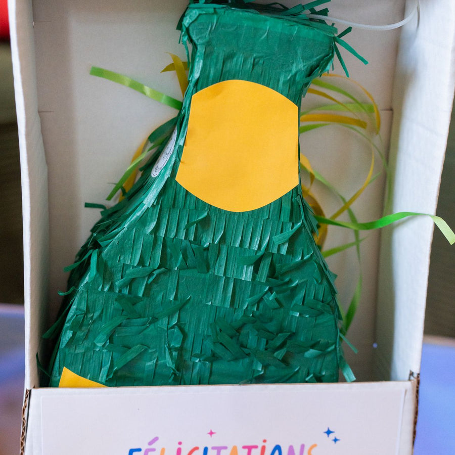 Piñata champagne en forme de bouteille avec bonbons colorés.