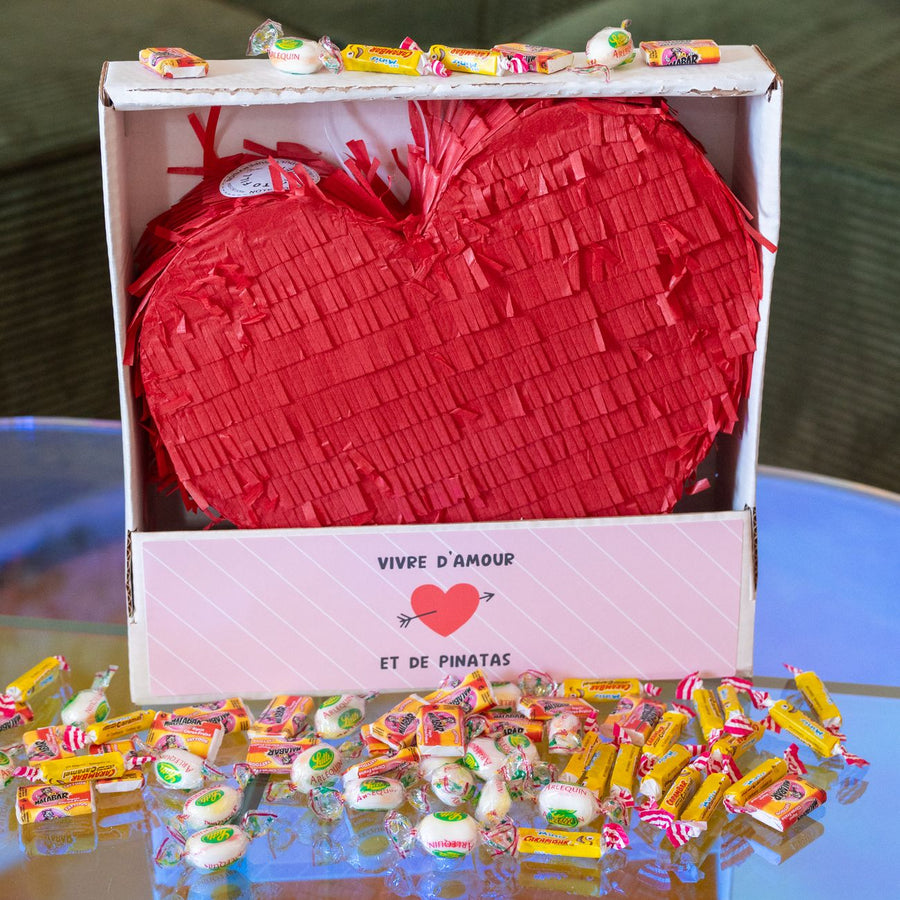 Piñata en forme de cœur avec bonbons colorés à l'intérieur.