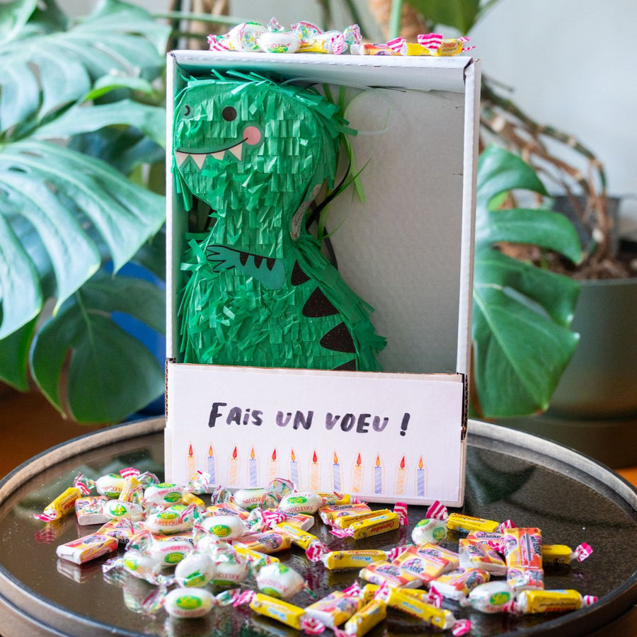 Piñata dinosaure colorée avec bonbons visibles à l'intérieur.