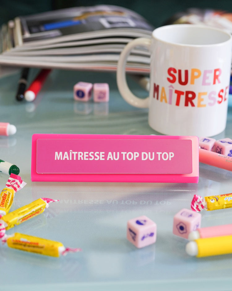 Plaque de bureau humoristique avec texte coloré sur fond clair.