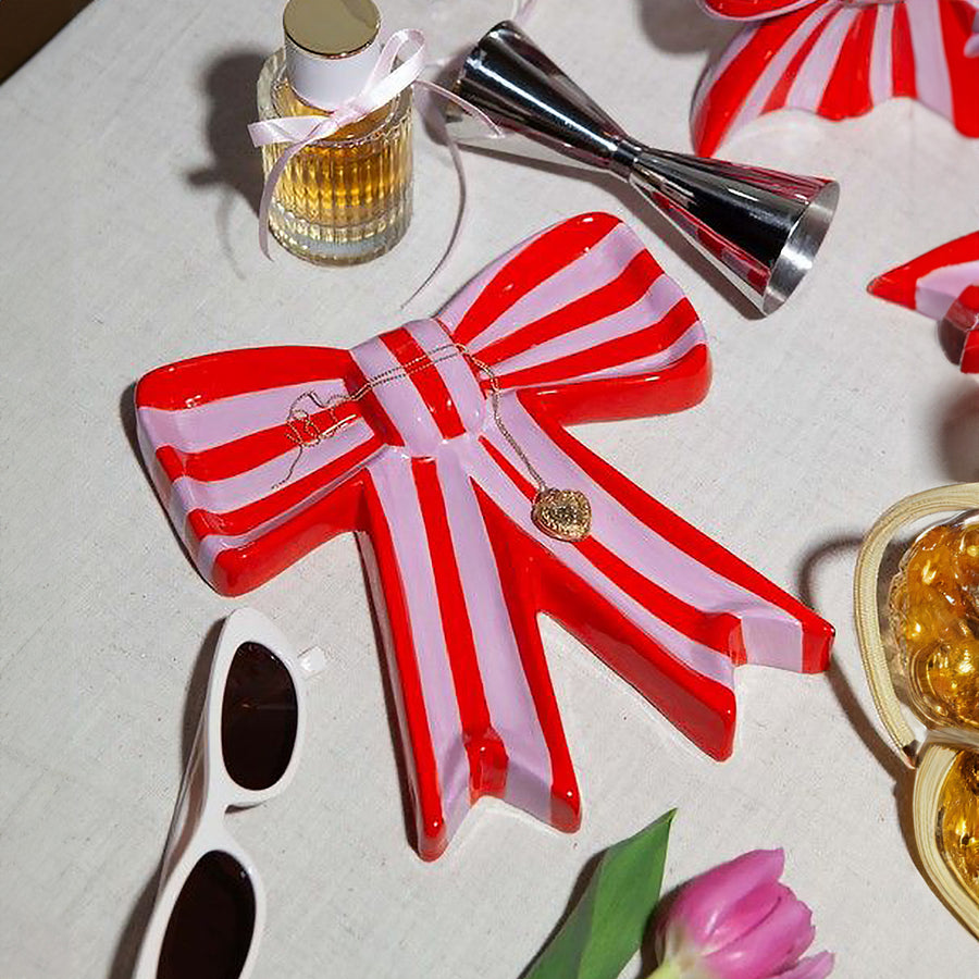 Vide poche en céramique rose avec motif nœud élégant.