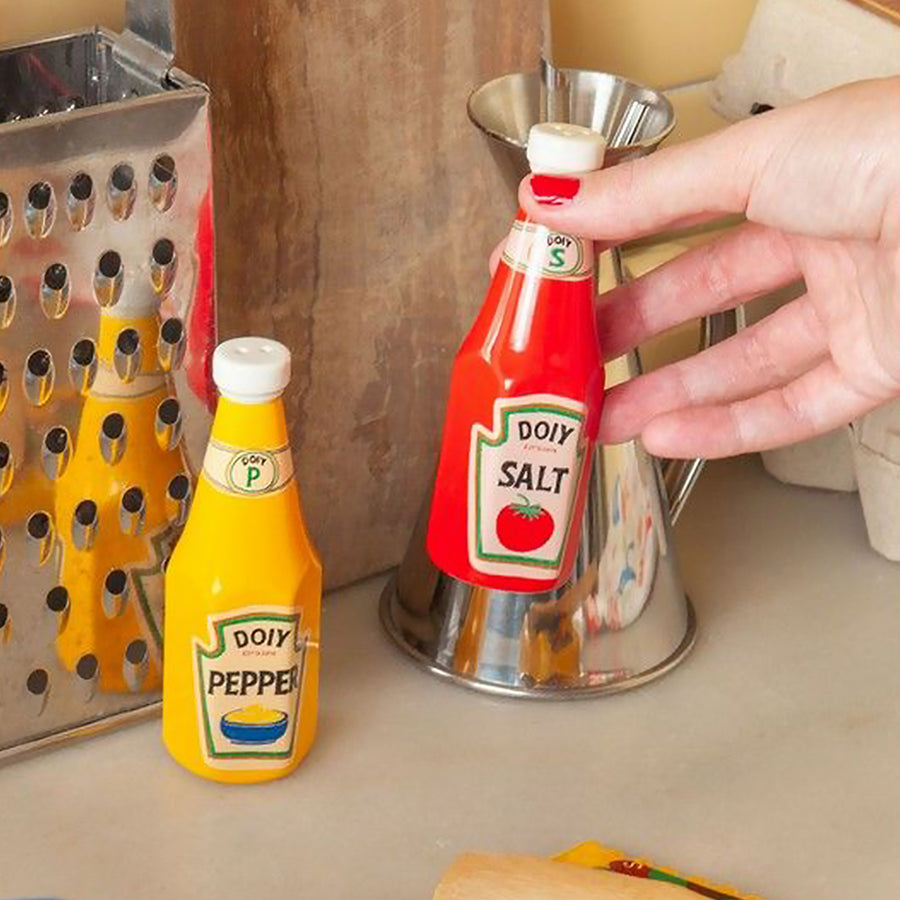 Salière et poivrière en forme de bouteilles de sauces vintage.