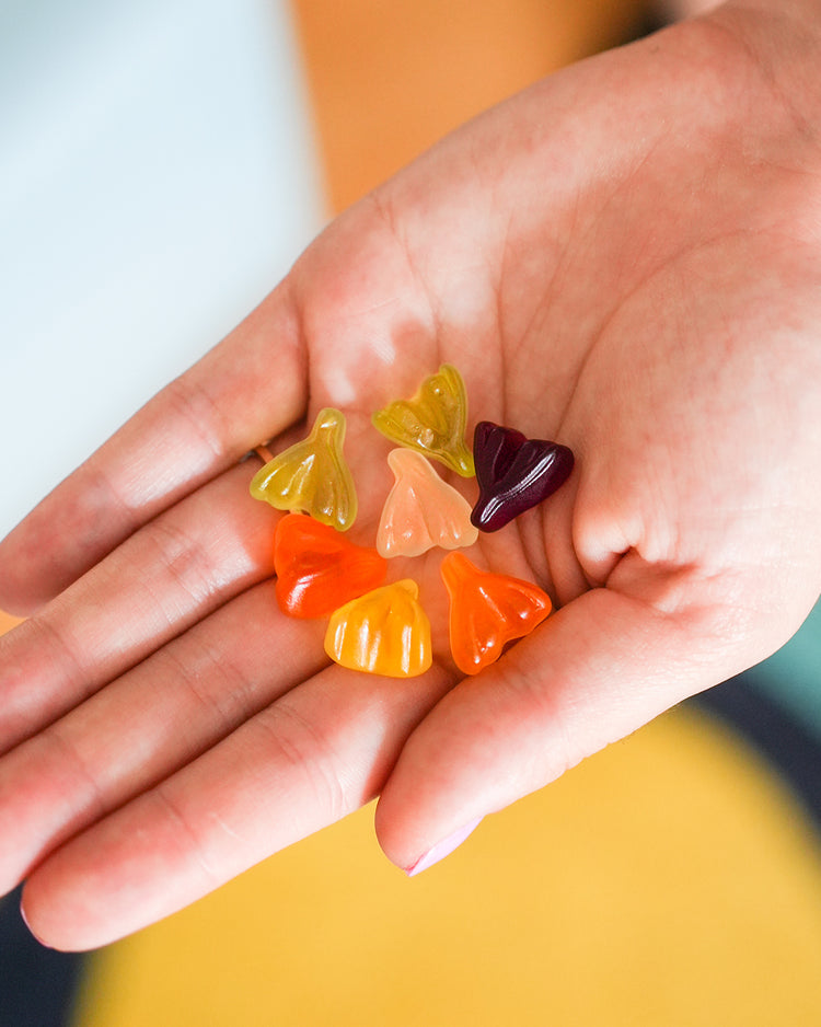 Bonbons en forme de clitoris colorés et sucrés sur fond blanc.