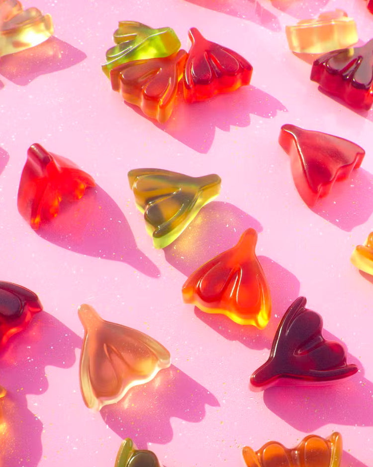 Bonbons en forme de clitoris colorés sur fond blanc