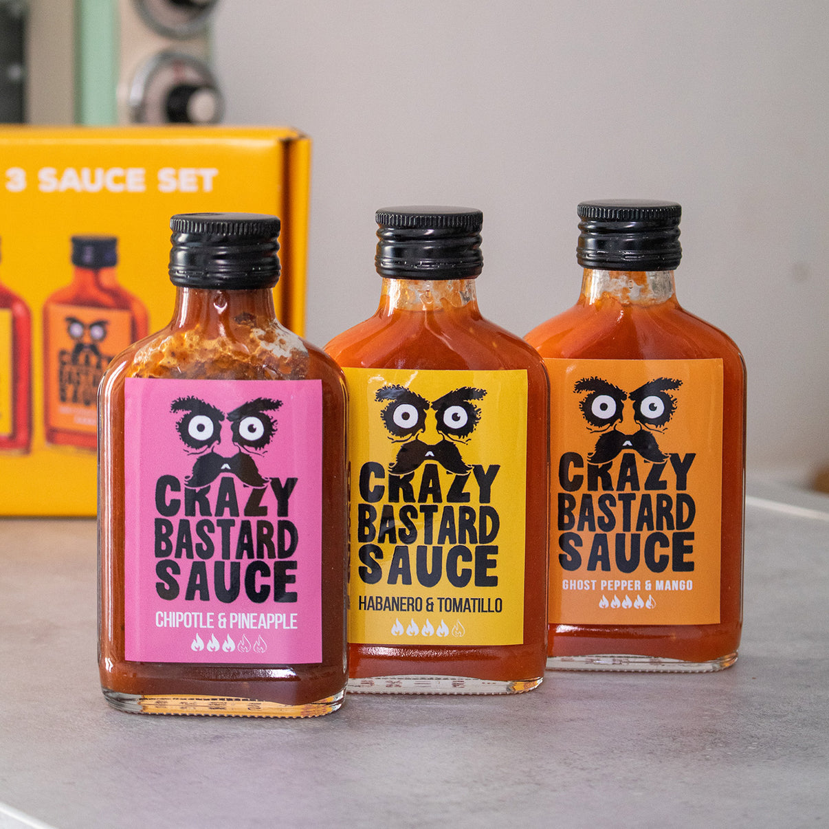 Trois flacons de sauces épicées sur fond blanc.