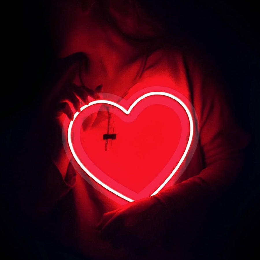 Néon en forme de cœur rouge éclatant sur fond neutre.