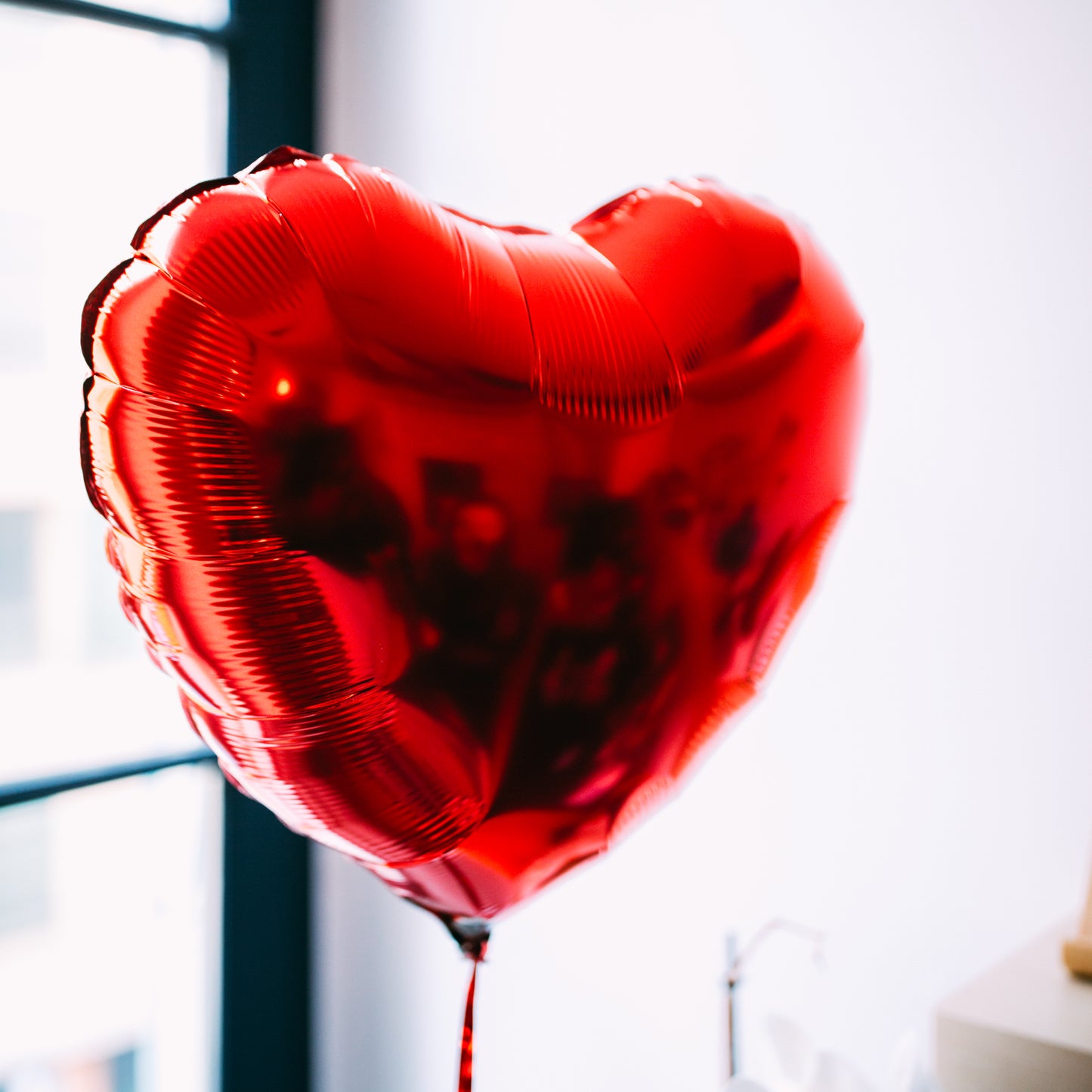 Ballon en forme de cœur rouge, texture lisse et brillante.