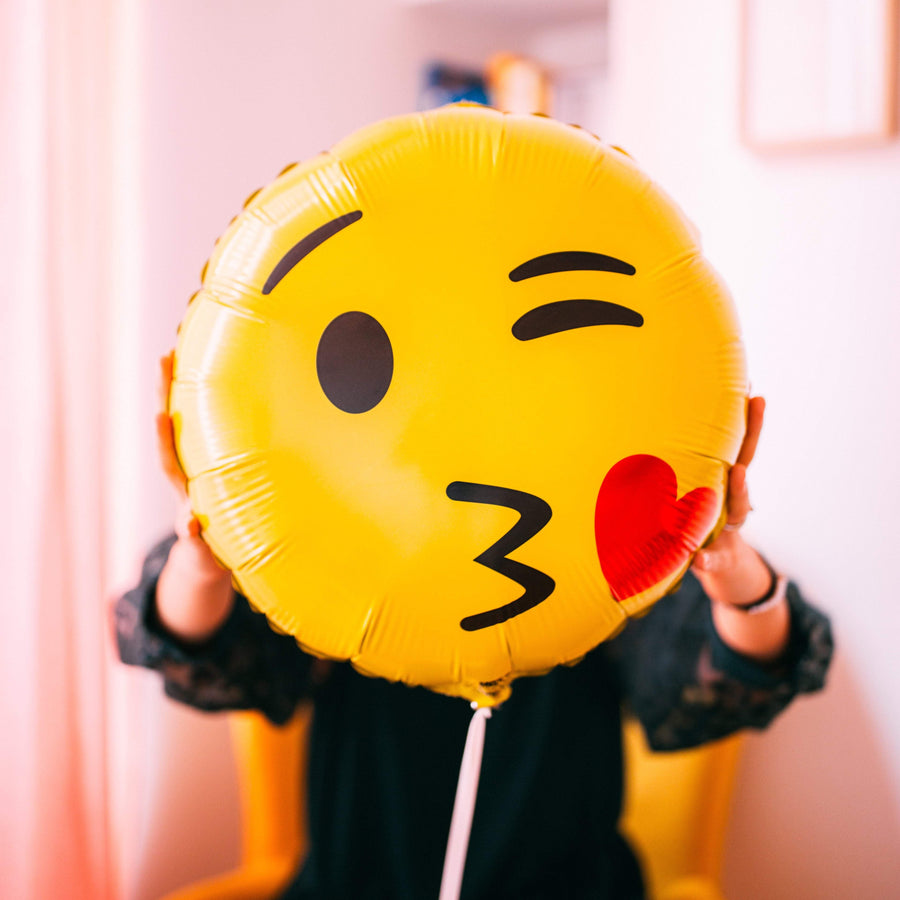 Ballon Emoji Bisous en forme de coeur rouge avec un visage souriant, idéal pour exprimer l'amour et la tendresse.